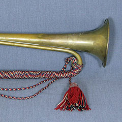 Bugle adorned with red, black and beige braided threads.