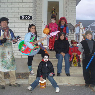 Une famille colombienne costumée pour l'Halloween posant devant une maison.