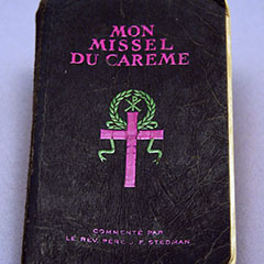 Black cover of a Lent missal on which there is a pink cross topped by a green laurel wreath.