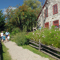 Une famille, composée de deux adultes et deux enfants, marche dans les sentiers menant au Moulin seigneurial de Pointe-du-Lac.
