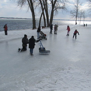 Des gens patinent sur un sentier gelé à proximité du fleuve Saint-Laurent.