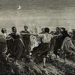 Young women dancing around a bonfire under the moonlight. Several other fires are lit in the background.