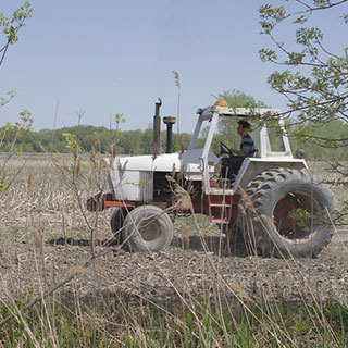Un homme conduit un tracteur dans un champ agricole.