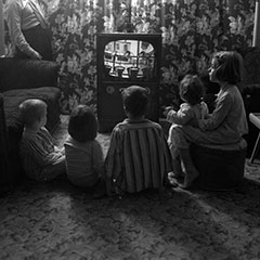 Des enfants sont assis devant un téléviseur.